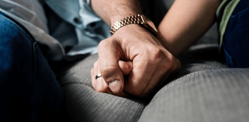 couple holding hands while sitting on the couch