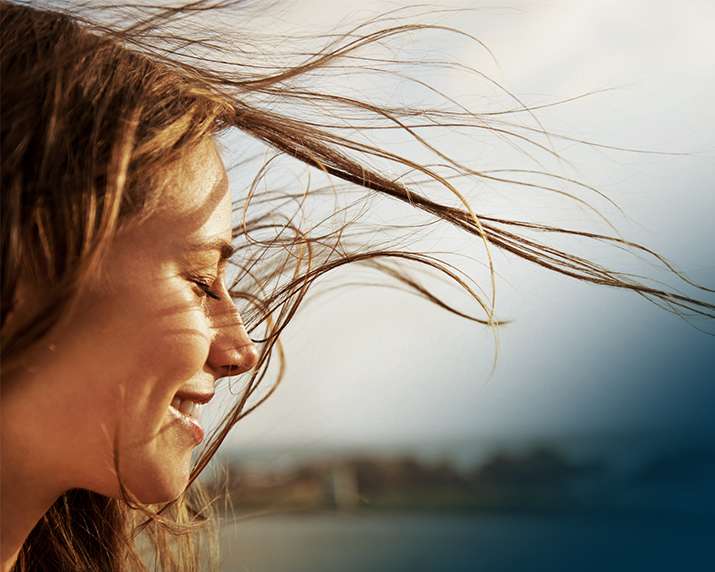 Wind blowing woman's hair with her eyes close