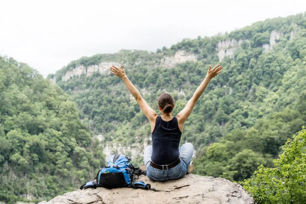 A woman sits on peak of mountain - tranquilshores.org